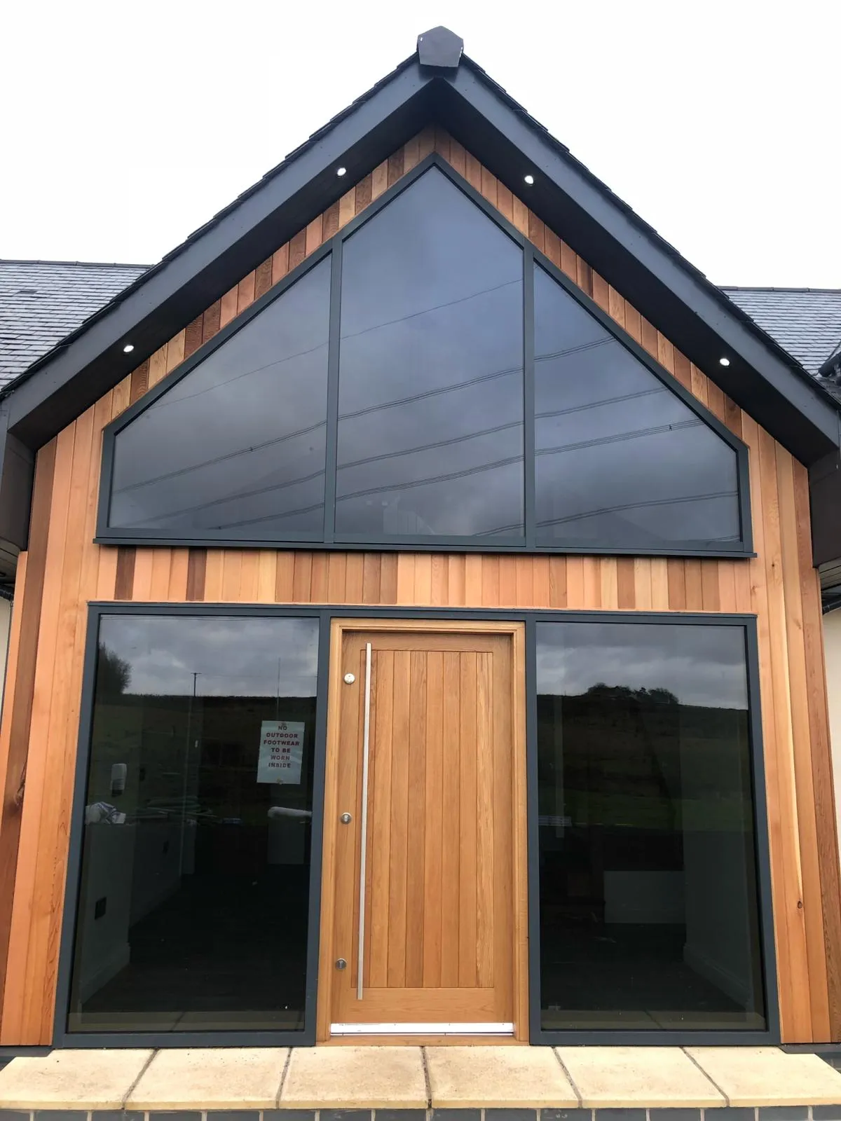 front entrance to a converted traditional rural scottish property showcasing solid timber door and aluminium glazed gable