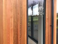 a converted traditional rural scottish property showcasing an aluminium window surrounded by wood cladding