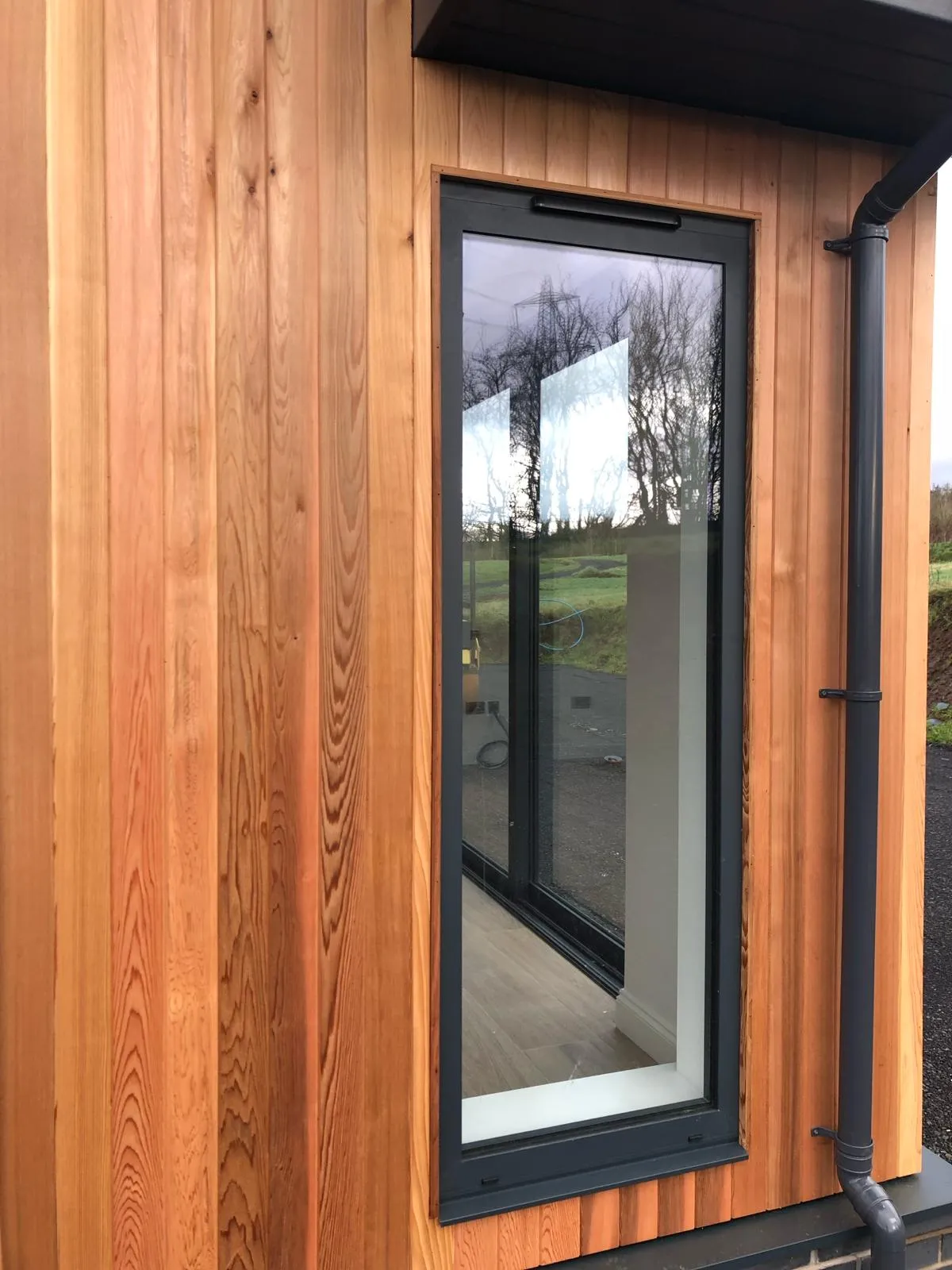 a converted traditional rural scottish property showcasing an aluminium window surrounded by wood cladding