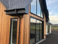 front entrance to a converted traditional rural scottish property showcasing solid timber door and aluminium glazed gable