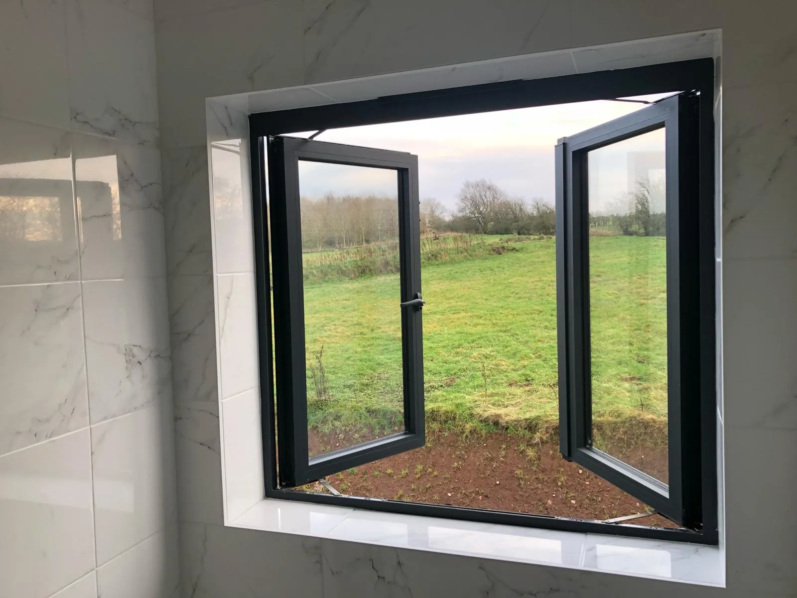 internal view from a gable windows of a converted traditional rural scottish property showcasing an aluminium juliet window - both panels open