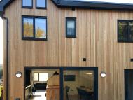 House clad in Scotch larch showing aluminium sliding doors and windows