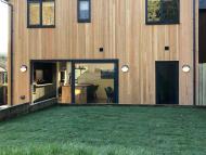 outside of a scotch larch clad house showcasing aluminium sliding doors and windows in textured grey finish and colour