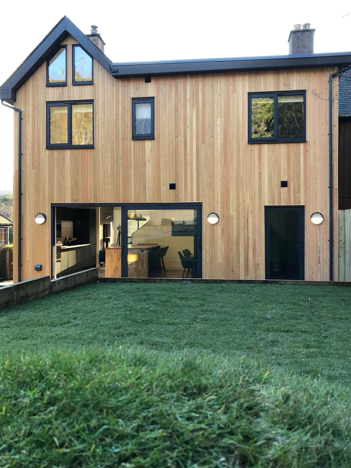 outside of a scotch larch clad house showcasing aluminium sliding doors and windows in textured grey finish and colour