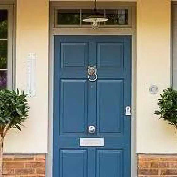 external, front on view of a blue timber front door with metal knocker and letter flap