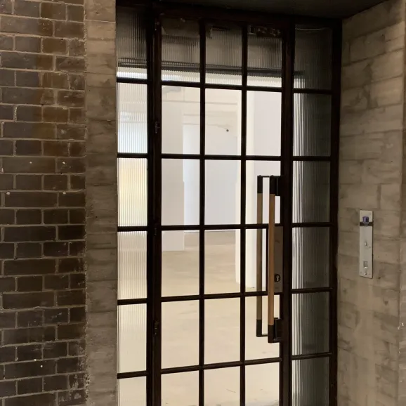 external view of a slim-line metal grid frame door with full door being apertures of frosted glass 