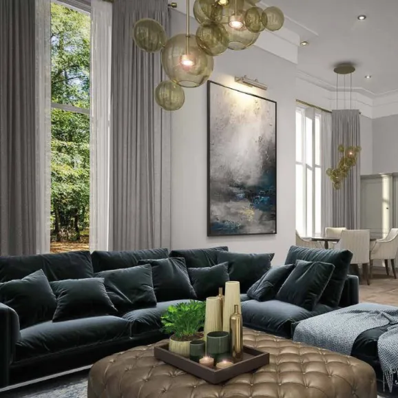 an elegant living room with a deep blue, plush velvet sofa and button-studed upholstered coffee table decorated with pillar candles and plant - a tall trad